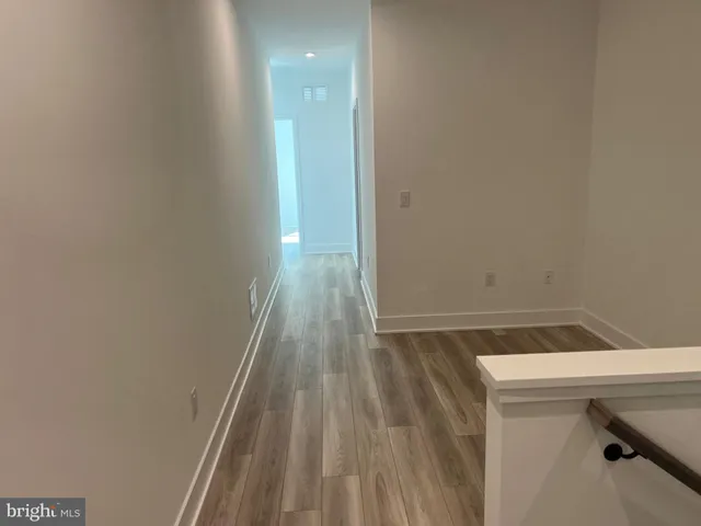 a view of hallway with a chair and frames on wall