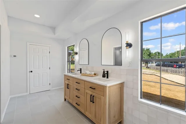 a bathroom with a double vanity sink a mirror and next to a window