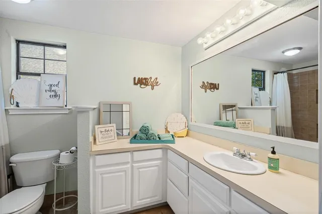 a bathroom with a granite countertop sink mirror vanity and toilet