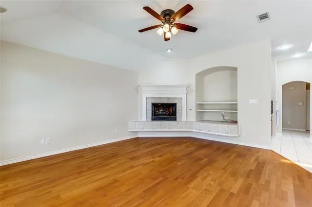 a view of empty room with wooden floor and fan