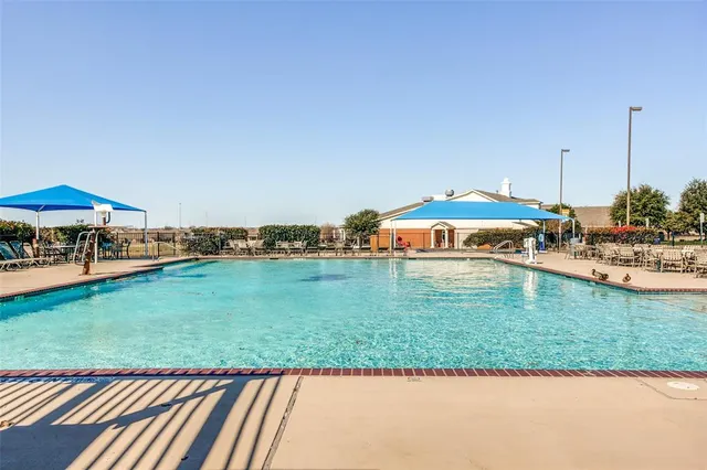 a view of a swimming pool with lawn chairs under an umbrella