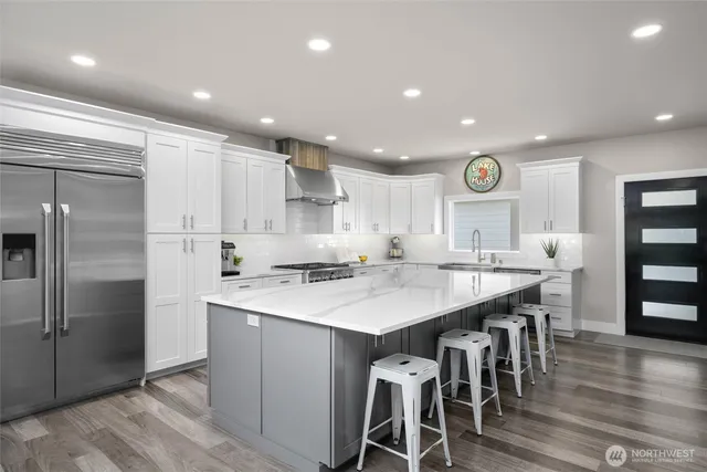 a large kitchen with a large counter top a sink stainless steel appliances and cabinets