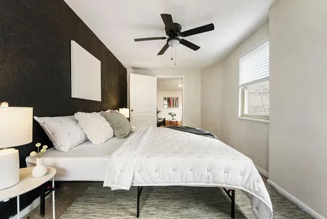 a bed room with a bed a dresser and a window