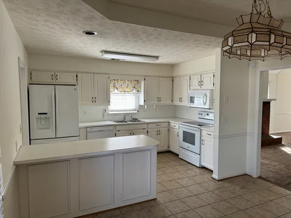 a kitchen with white cabinets and white appliances