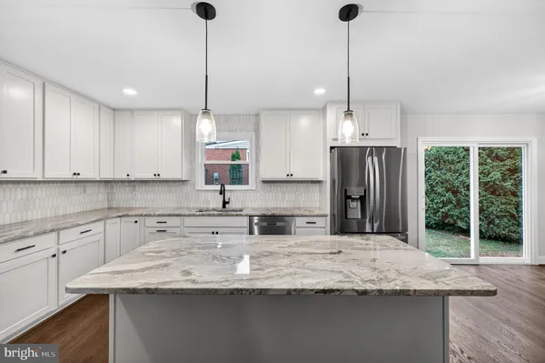 a kitchen with kitchen island granite countertop a sink a counter top space stainless steel appliances and cabinets