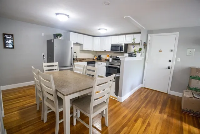 a kitchen with stainless steel appliances granite countertop a refrigerator a stove top oven a sink dishwasher and white cabinets with wooden floor