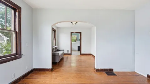 a view of a hallway with wooden floor and a bathroom