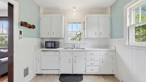 a kitchen with white cabinets and a window