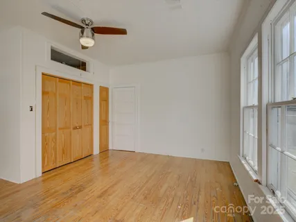 a view of empty room with wooden floor and fan