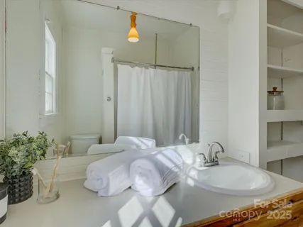 an empty room with chandelier fan and windows