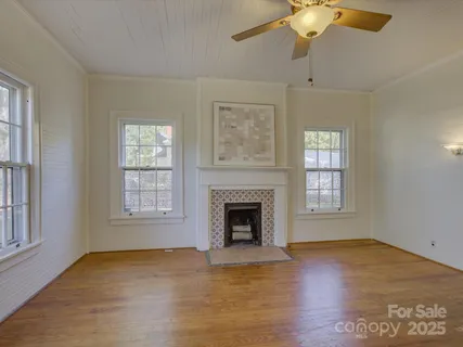 an empty room with windows fireplace and wooden floor