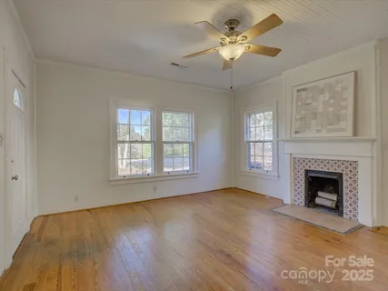 a view of an empty room with chandelier fan and a fireplace