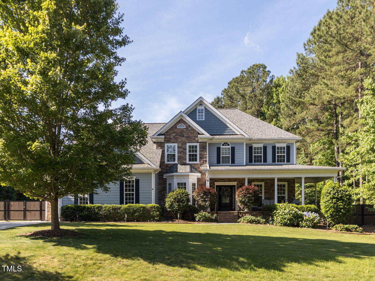 a front view of a house with a garden and trees