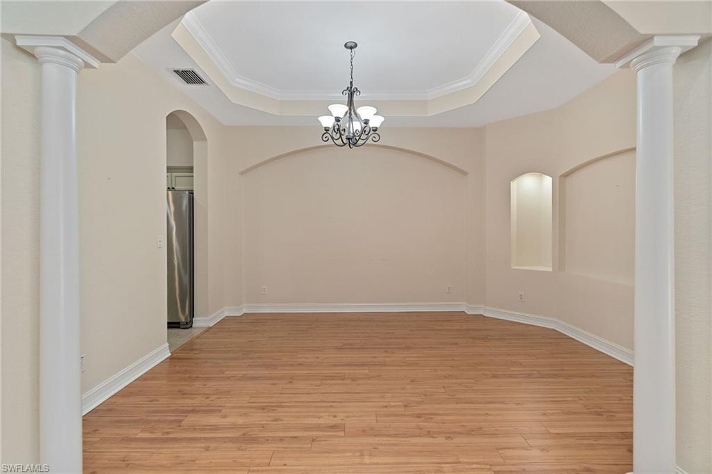 1158 Oakes Boulevard Naples, FL 34119 - Photo 12 of 40 Dining area featuring decorative columns, arched walkways, light wood-type flooring, crown molding, and a chandelier