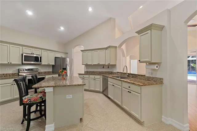 a kitchen with stainless steel appliances granite countertop a stove top oven a sink dishwasher a dining table and chairs with wooden floor