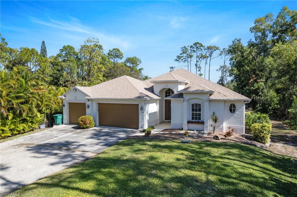 1158 Oakes Boulevard Naples, FL 34119 - Photo 2 of 40 View of front facade featuring a shingled roof, an attached garage, stucco siding, and concrete pad