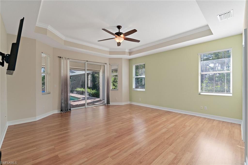 1158 Oakes Boulevard Naples, FL 34119 - Photo 23 of 40 Unfurnished Main Bedroom featuring crown molding, light wood-style flooring, ceiling fan, ensuite bath & tray ceiling