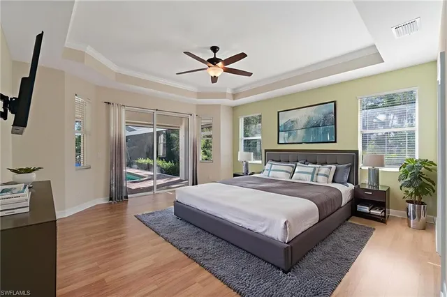 a spacious bedroom with a large bed a chandelier and windows