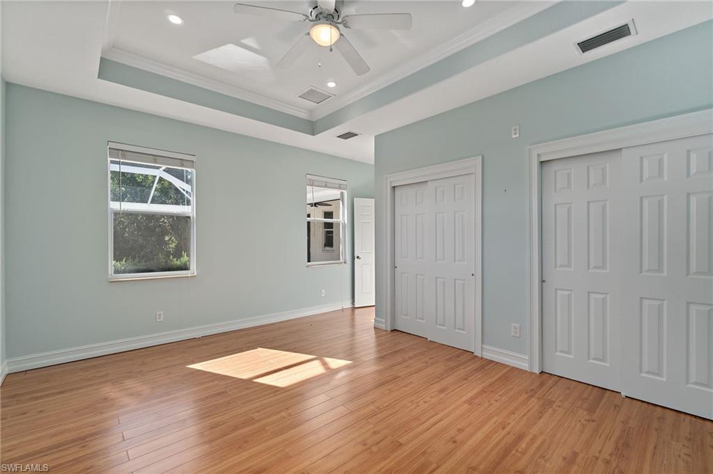 1158 Oakes Boulevard Naples, FL 34119 - Photo 32 of 40 Unfurnished bedroom featuring multiple closets, light wood-style floors, a raised ceiling, ceiling fan, and crown molding