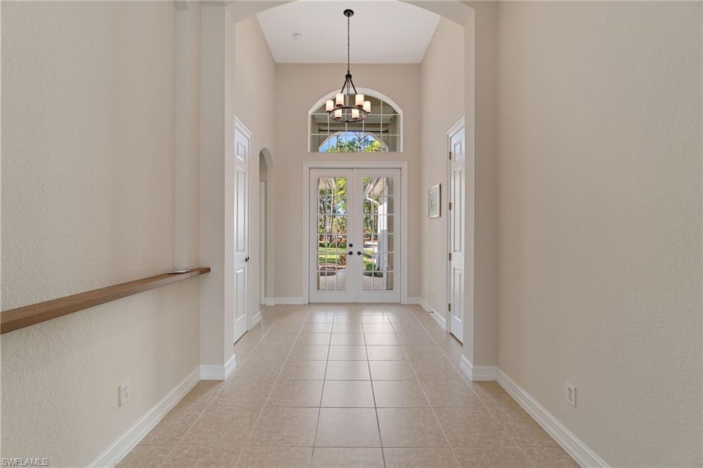 1158 Oakes Boulevard Naples, FL 34119 - Photo 5 of 40 Foyer entrance with arched walkways, french doors, a high ceiling, light tile patterned floors, and a chandelier