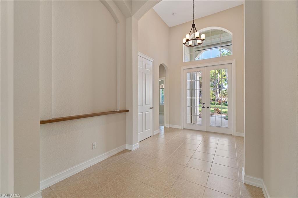 1158 Oakes Boulevard Naples, FL 34119 - Photo 6 of 40 Foyer entrance with french doors, arched walkways, a towering ceiling, light tile patterned floors, and a chandelier