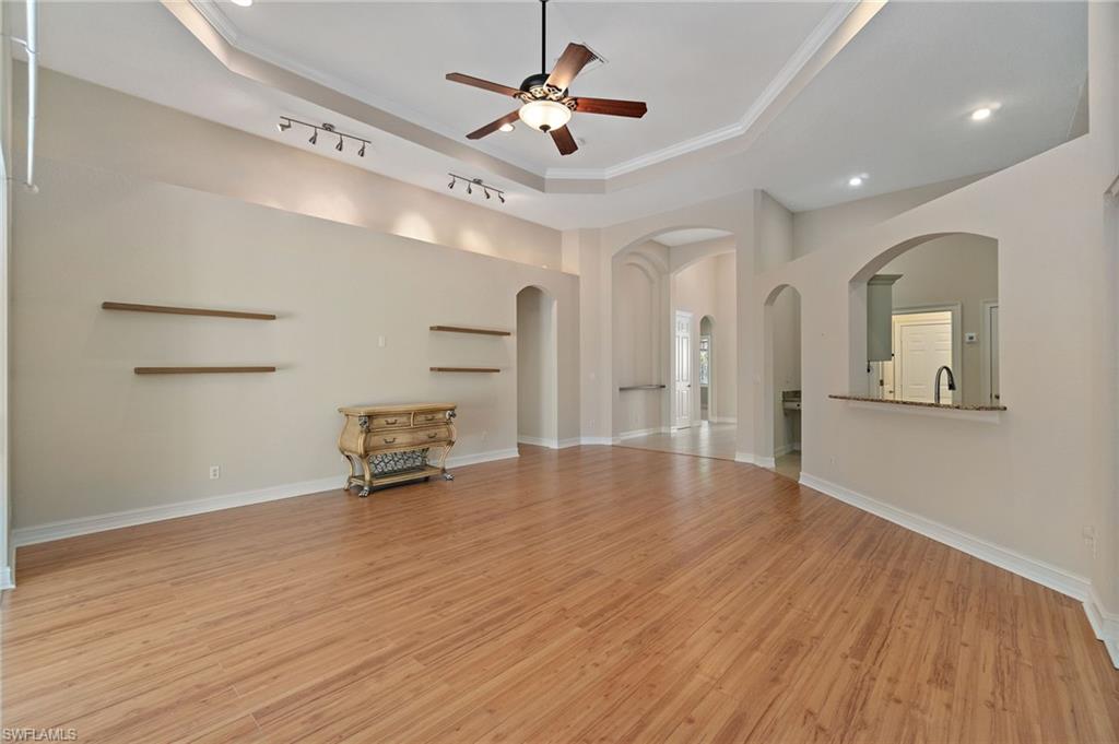 1158 Oakes Boulevard Naples, FL 34119 - Photo 7 of 40 Unfurnished living room with a raised ceiling, light wood-style floors, ornamental molding, a ceiling fan, and arched walkways