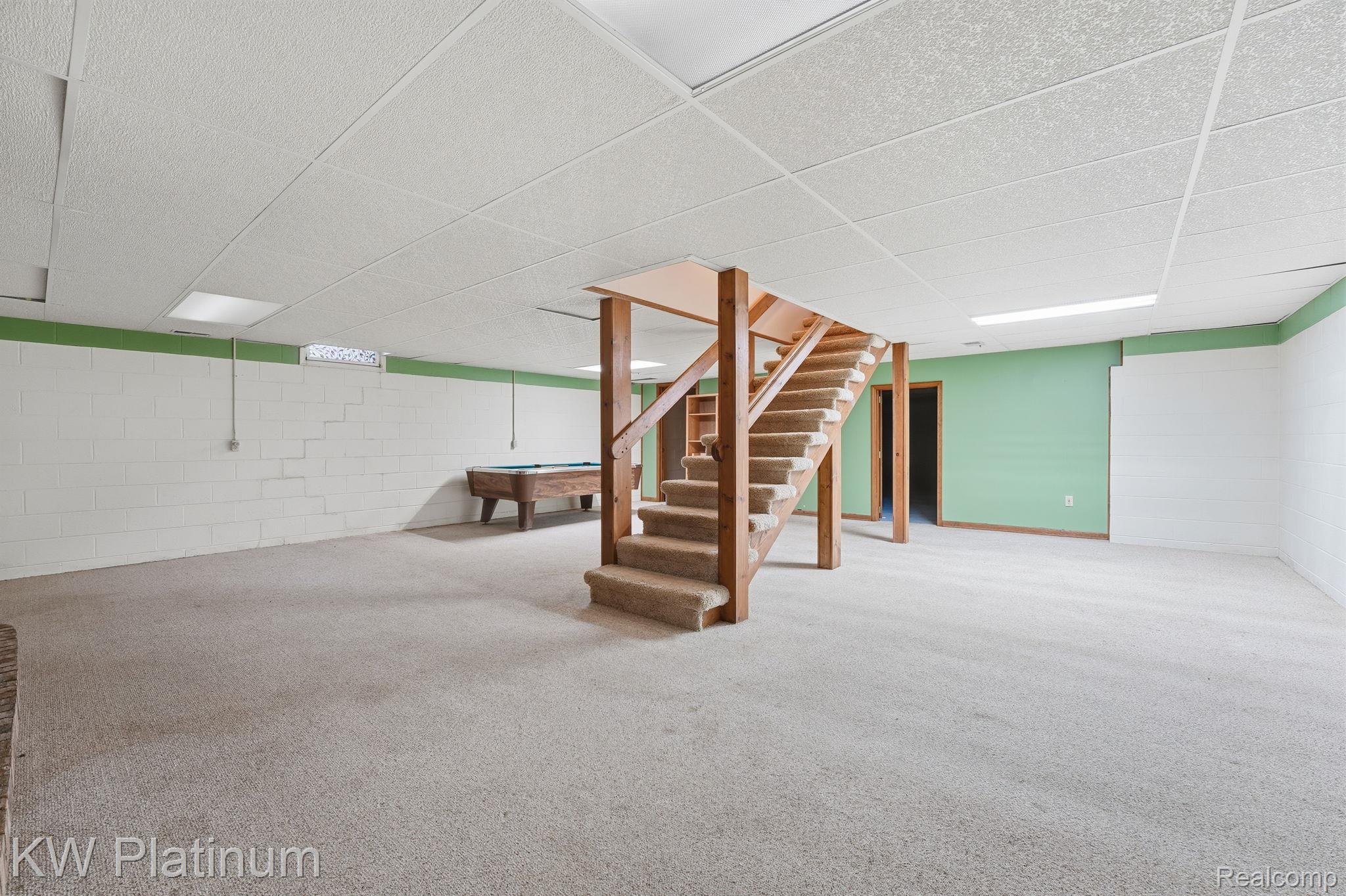 7383 Fisher Road Jeddo, MI 48032 - Photo 21 of 40 Finished basement featuring a drop ceiling, billiards, concrete block wall, carpet flooring, and stairway