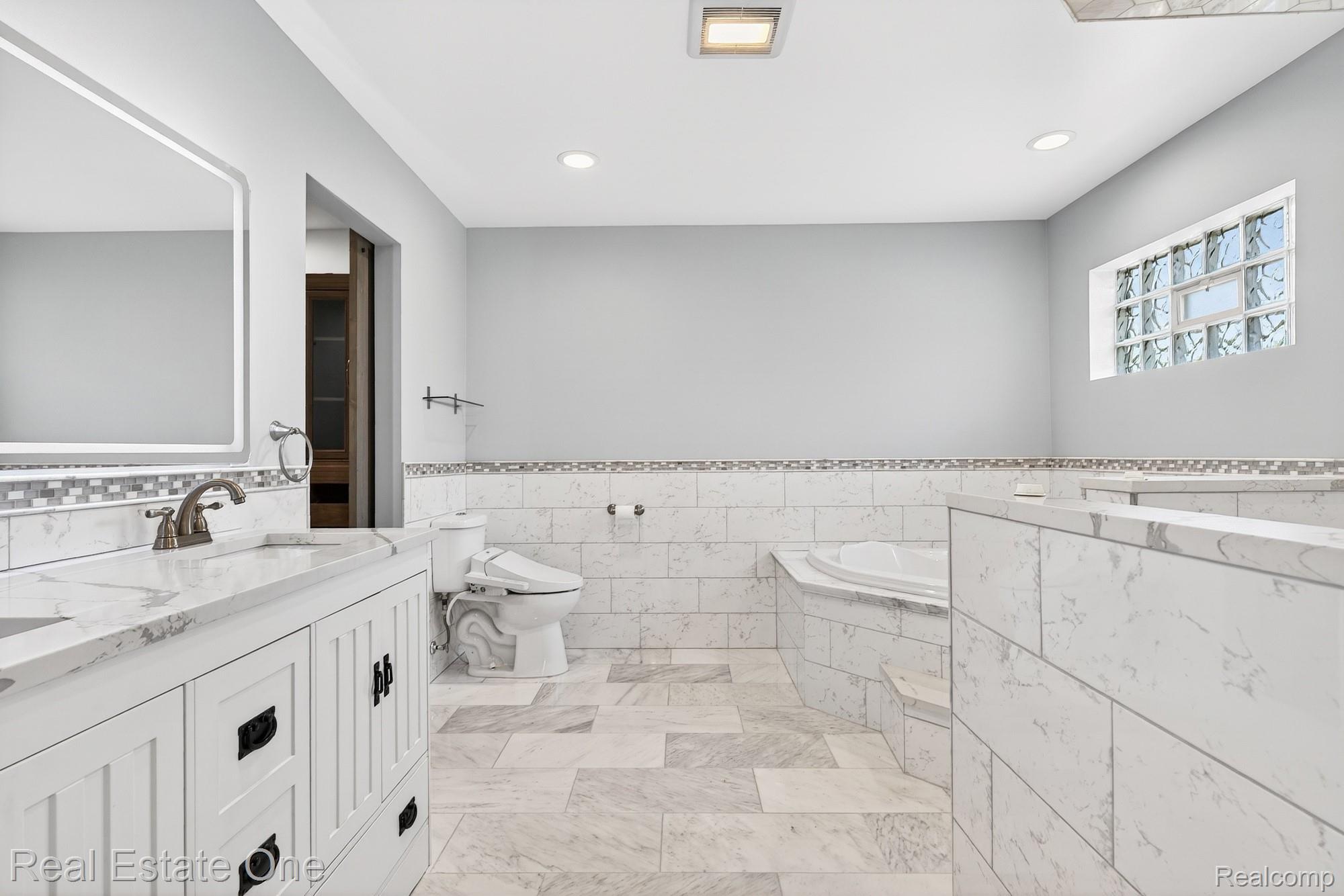 26987 Crawford Road Romulus, MI 48174 - Photo 22 of 51 White shaker-style vanity with a double sink and an illuminated mirror