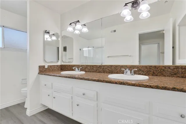 a bathroom with double vanity sinks a vanity a lamp and a mirror