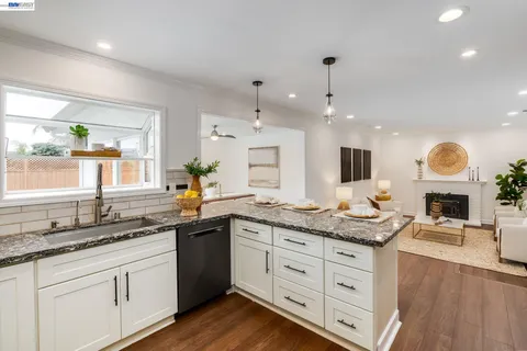 a kitchen with granite countertop a sink white cabinets and a dishwasher