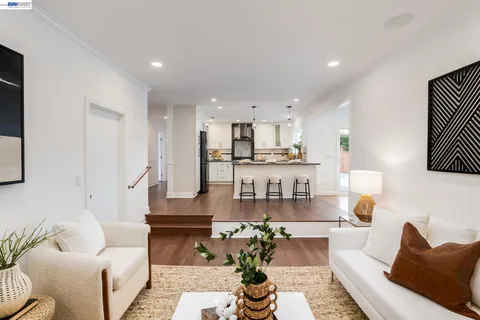 a living room with stainless steel appliances furniture and a wooden floor