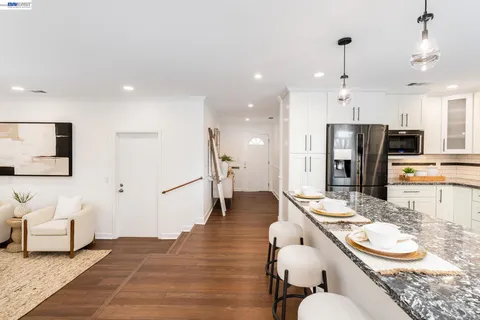 a dining room with stainless steel appliances furniture a rug and a kitchen view