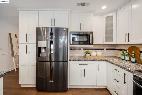 a kitchen with granite countertop a refrigerator stove and microwave