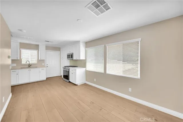 a large white kitchen with white cabinets and wooden floors