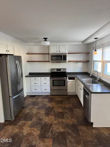 a kitchen with stainless steel appliances granite countertop a refrigerator a stove a sink and a microwave