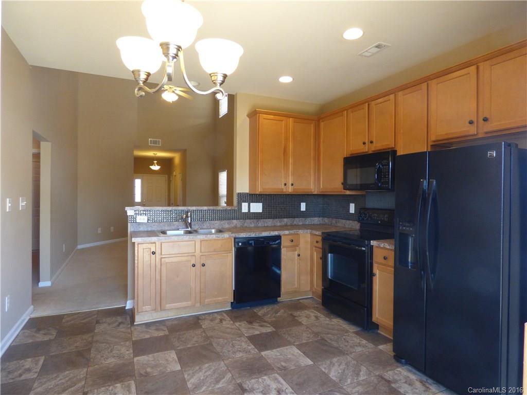 1249 Afternoon Sun Road Matthews, NC 28104 - Photo 9 of 20 a kitchen with stainless steel appliances granite countertop a refrigerator a sink dishwasher a stove and a dining table with wooden floor