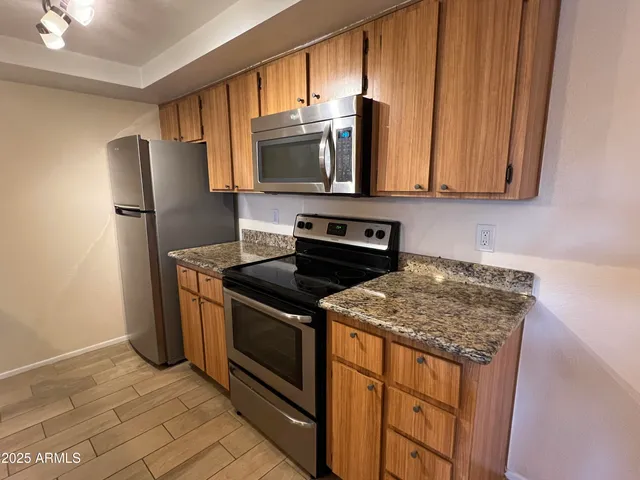 a kitchen with stainless steel appliances granite countertop a stove microwave refrigerator and sink