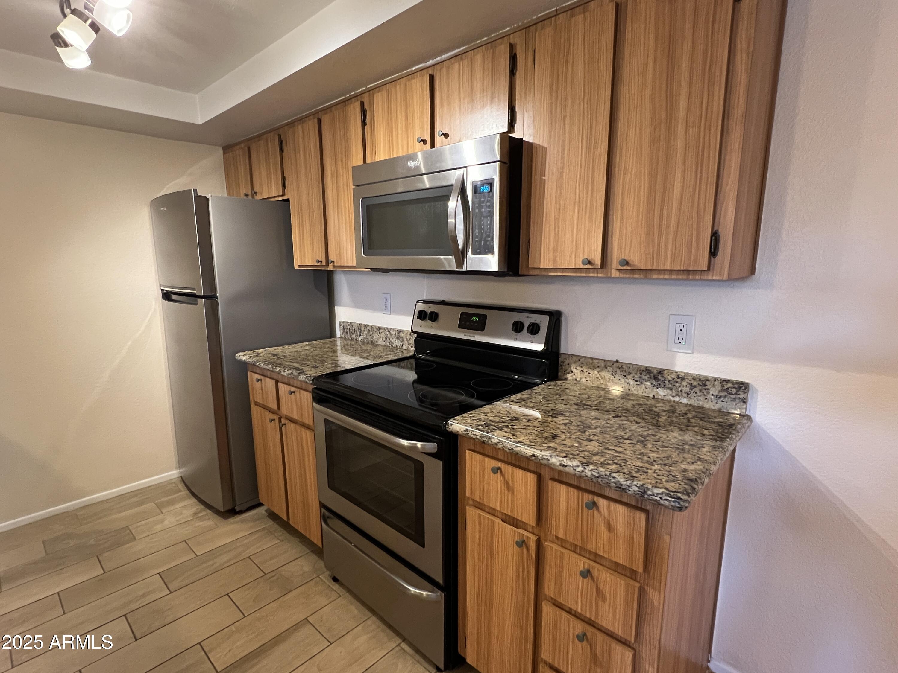 1125 East Broadway Road, Unit 102 Tempe, AZ 85282 - Photo 6 of 10 a kitchen with stainless steel appliances granite countertop a stove microwave refrigerator and sink