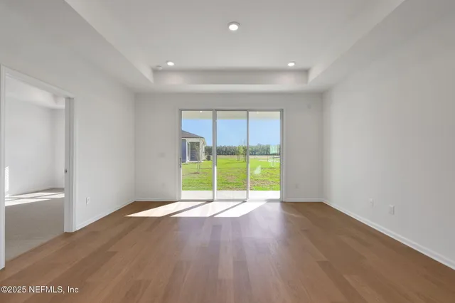 a view of an empty room with a window and wooden floor