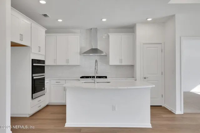 a kitchen with kitchen island a stove a sink a refrigerator and white cabinets