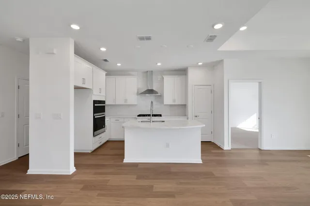 a large kitchen with kitchen island a sink a stove a refrigerator and white cabinets