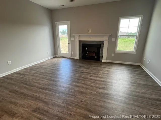 an empty room with wooden floor fireplace and windows