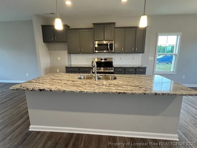 a kitchen with kitchen island granite countertop a sink cabinets and stainless steel appliances