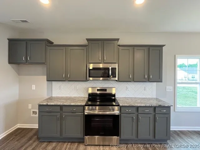 a kitchen with granite countertop a stove a sink and a microwave