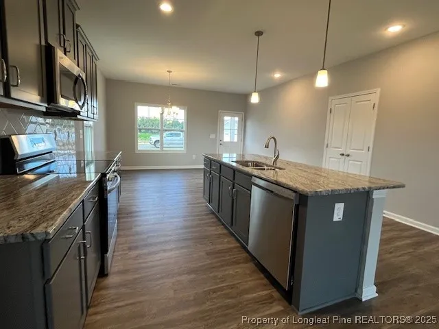 a kitchen with stainless steel appliances granite countertop wooden cabinets a sink a stove and a wooden floors