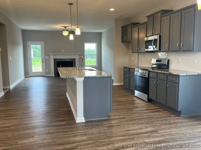 a kitchen with stainless steel appliances granite countertop a stove top oven a refrigerator a sink dishwasher and wooden cabinets with wooden floor