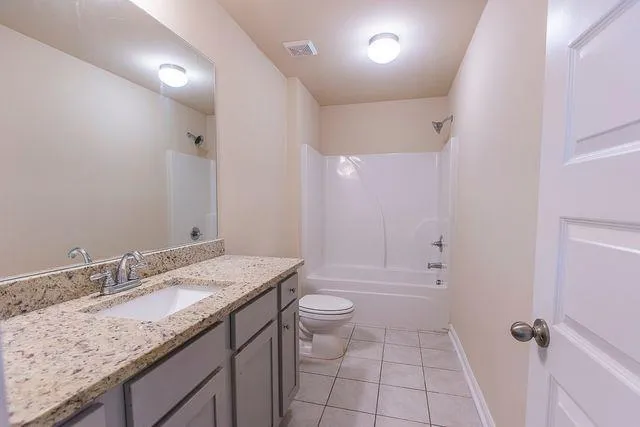 a bathroom with a granite countertop sink a toilet and shower