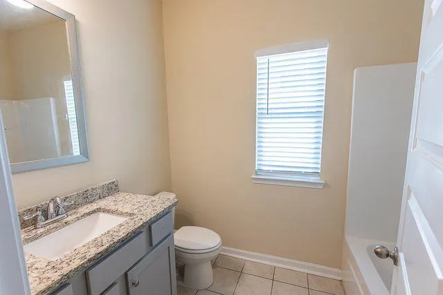 a bathroom with a granite countertop sink toilet and mirror