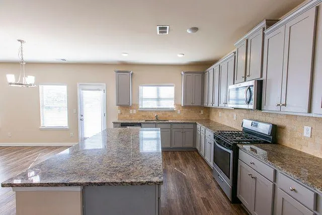 a kitchen with stainless steel appliances granite countertop a sink stove and cabinets