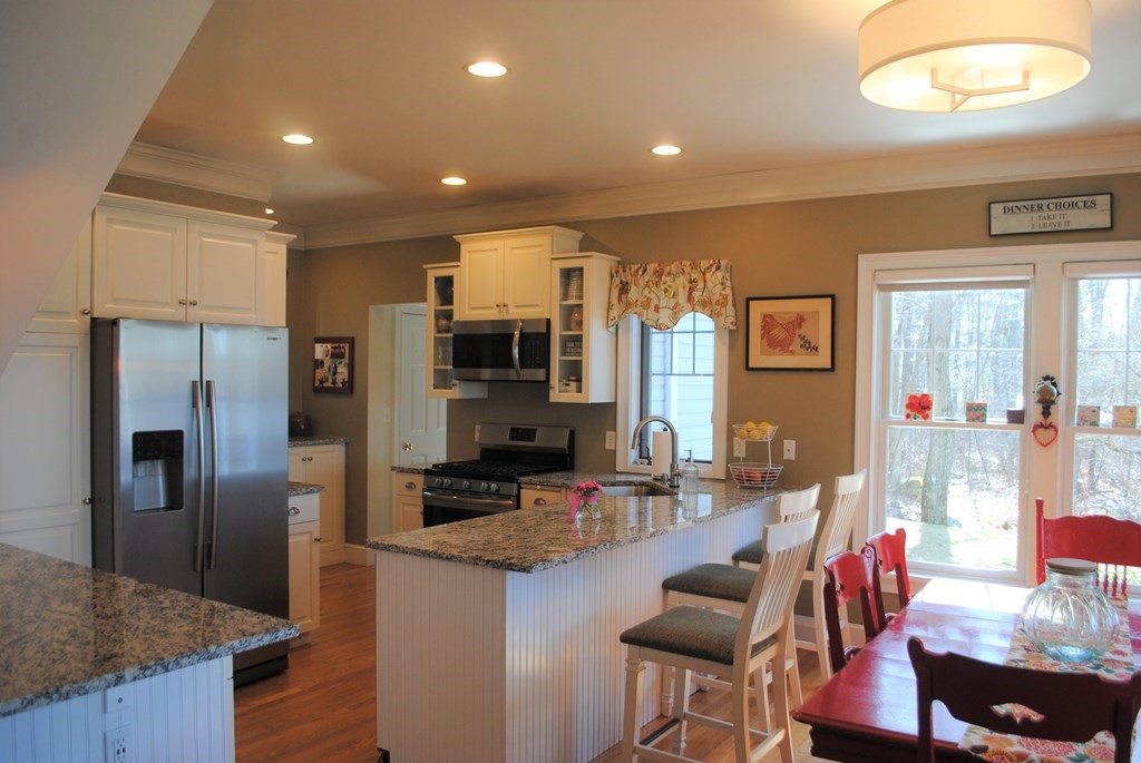 518 Douglas Road Northbridge, MA 01588 - Photo 5 of 41 a kitchen with stainless steel appliances kitchen island granite countertop a refrigerator a stove and a dining table with wooden floor